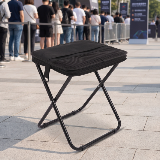 Black portable handbag folding stool beside an outdoor event queue